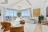 Floor-to-ceiling windows, recessed cove lighting, wood-finish flooring, and a private balcony