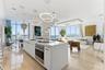 Open concept kitchen featuring a stone-topped island, stainless steel built-in oven, contemporary ring chandeliers, polished stone flooring, and a str