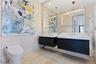 Floating dual vanity with integrated white basins, illuminated rectangular mirrors, full-wall stone-tile surfacing, and a sleek low-profile toilet
