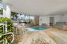 Covered outdoor patio featuring natural stone flooring, a recessed oval pool with metal handrails, and structural support columns