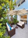 Private patio featuring light grey tile flooring, horizontal lap siding, and mature tropical landscaping