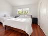 Vaulted ceiling, wood-finish flooring, horizontal window with white window shades, and built-in closet with double doors