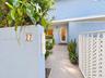 Private entryway featuring stucco perimeter walls, horizontal lap siding, tiled walkway, and a white lattice fence