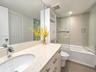 Bathroom featuring a solid-surface countertop with an integrated basin, high-gloss cabinetry, built-in shelving, a full-width vanity mirror, and a til
