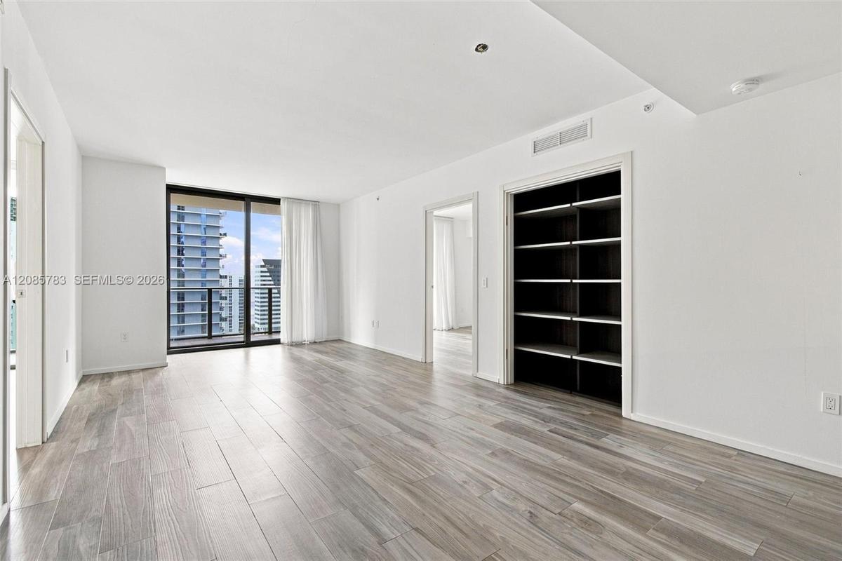 Wood-finish flooring, floor-to-ceiling glass sliding doors, built-in shelving, and recessed lighting