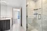 Bathroom featuring stone-finish flooring, glass-enclosed shower with full-height stone-finish wall tile, and vanity with stone-finish countertop