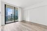 Floor-to-ceiling sliding glass door, private balcony with metal railing, and wood-finish flooring