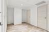 Interior space featuring tray ceiling, wood-finish flooring, and two interior doors with horizontal grain finish