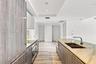 Kitchen featuring wood-finish cabinetry, natural stone countertops, a double-basin undermount sink with a gooseneck faucet, integrated stainless steel
