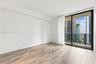 Wood-finish flooring, floor-to-ceiling glass sliding doors, and a private balcony with high-rise urban surroundings