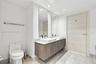Floating vanity with dual rectangular vessel sinks, stone-surface countertop, full-height wall mirrors, and wood-finish door