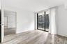 Wood-finish flooring, full-height sliding glass doors, private balcony, and neutral wall finishes