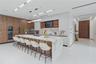 Modern kitchen featuring flat-panel wood-finish cabinetry, a large waterfall island with stone countertop, built-in stainless steel appliances, integr