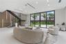 Open-concept interior featuring large-format tile flooring, a custom metal staircase with a glass railing, built-in decorative wall paneling, and floo