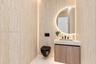 Full-height stone-finish wall tiling, wall-mounted matte black toilet, floating wood-finish vanity with integrated stone-finish basin, matte black wid