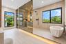 Bathroom featuring a freestanding oval soaking tub, expansive glass-enclosed shower, wood-finish wall and floor tiling, matte black fixtures, and rece