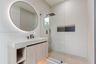 Floating vanity with integrated sink, textured wall tile, circular backlit mirror, frameless glass shower enclosure with rainfall showerhead, and herr