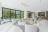 Open-concept interior featuring large-format flooring, expansive floor-to-ceiling sliding glass doors, recessed linear lighting, and built-in wood cab