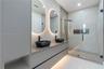 Floating dual-sink vanity with matte black fixtures, quartz-finish countertop, backlit oval mirrors, and a walk-in glass-enclosed shower featuring a b