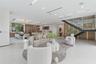 Open-concept floor plan featuring expansive stone-tile flooring, recessed linear lighting, custom wood-paneled cabinetry, and a floating staircase wit