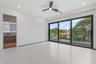Large-format porcelain tile flooring, expansive floor-to-ceiling sliding glass doors with black frames, recessed LED lighting, three-blade ceiling fan