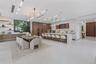 Open-concept kitchen featuring a waterfall-edge stone island, built-in panel-ready appliances, wood-finish cabinetry, linear recessed ceiling lighting