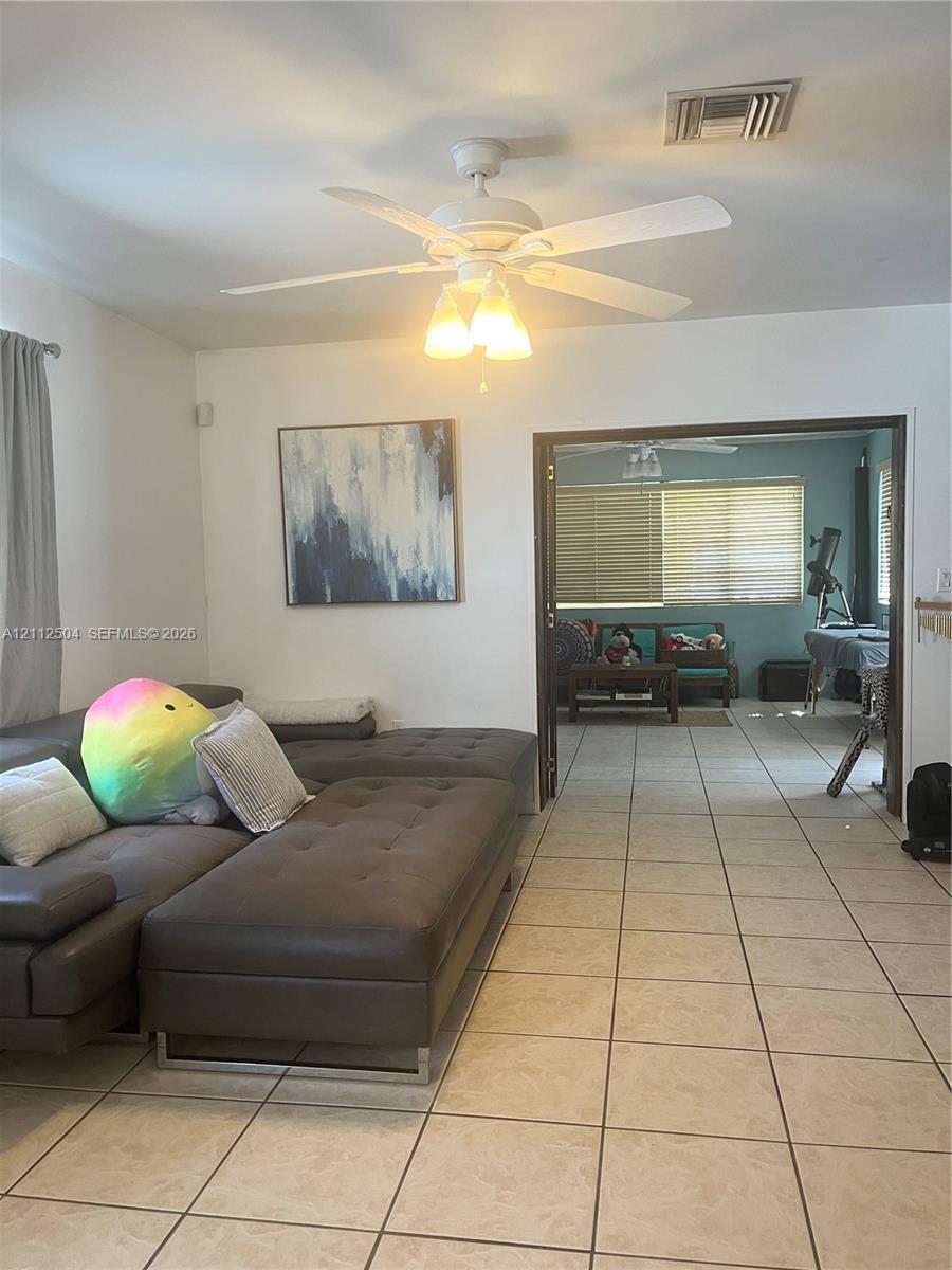 Ceramic tile flooring, white ceiling fan with integrated light fixture, and wide entryway featuring double doors