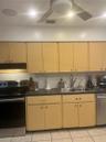 Light wood cabinetry, subway tile backsplash, stainless steel appliances, dark countertops, and ceiling-mounted light fixture