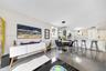 Open-concept interior featuring large-format tile flooring, recessed lighting, a modern multi-ring chandelier, and a kitchen island with integrated se