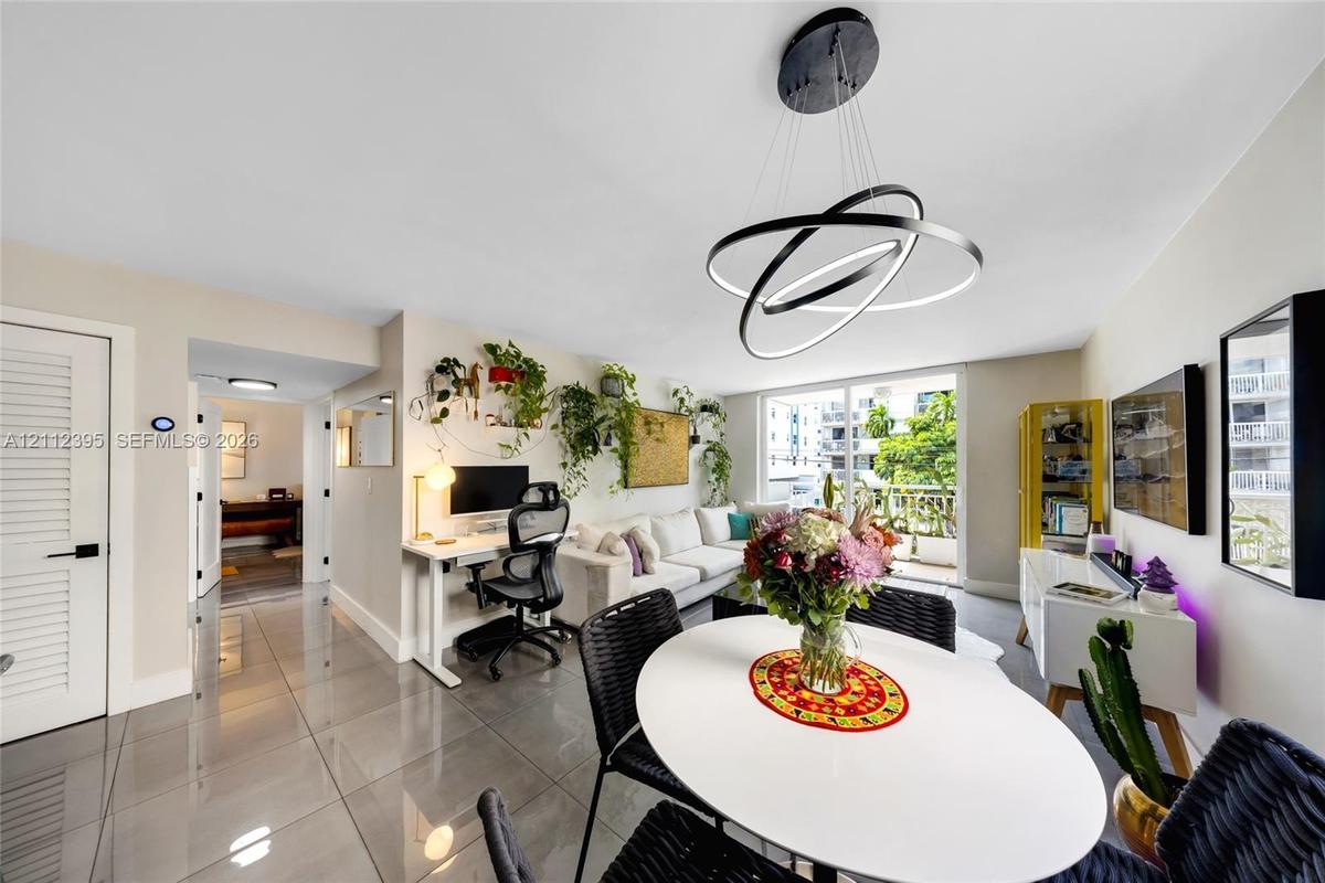 Living area featuring polished large-format floor tiles, contemporary multi-ring circular pendant lighting, and glass sliding doors providing external