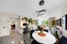 Living area featuring polished large-format floor tiles, contemporary multi-ring circular pendant lighting, and glass sliding doors providing external