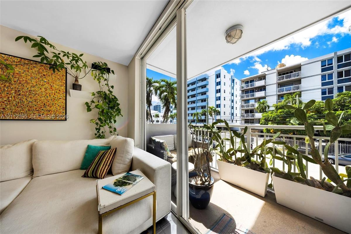 Covered balcony with floor-to-ceiling sliding glass doors, flush-mount lighting, and metal railing