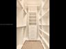 Organized walk-in closet with custom white built-ins, hanging rods, adjustable shelving, and a built-in four-drawer dresser