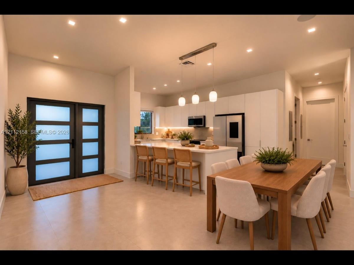 Open dining and kitchen area with stone countertops, recessed lighting, and a frosted-glass door that adds style and privacy