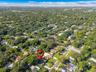 Aerial view of the property on a generous lot with a paved driveway and mature trees in a quiet, low-density neighborhood