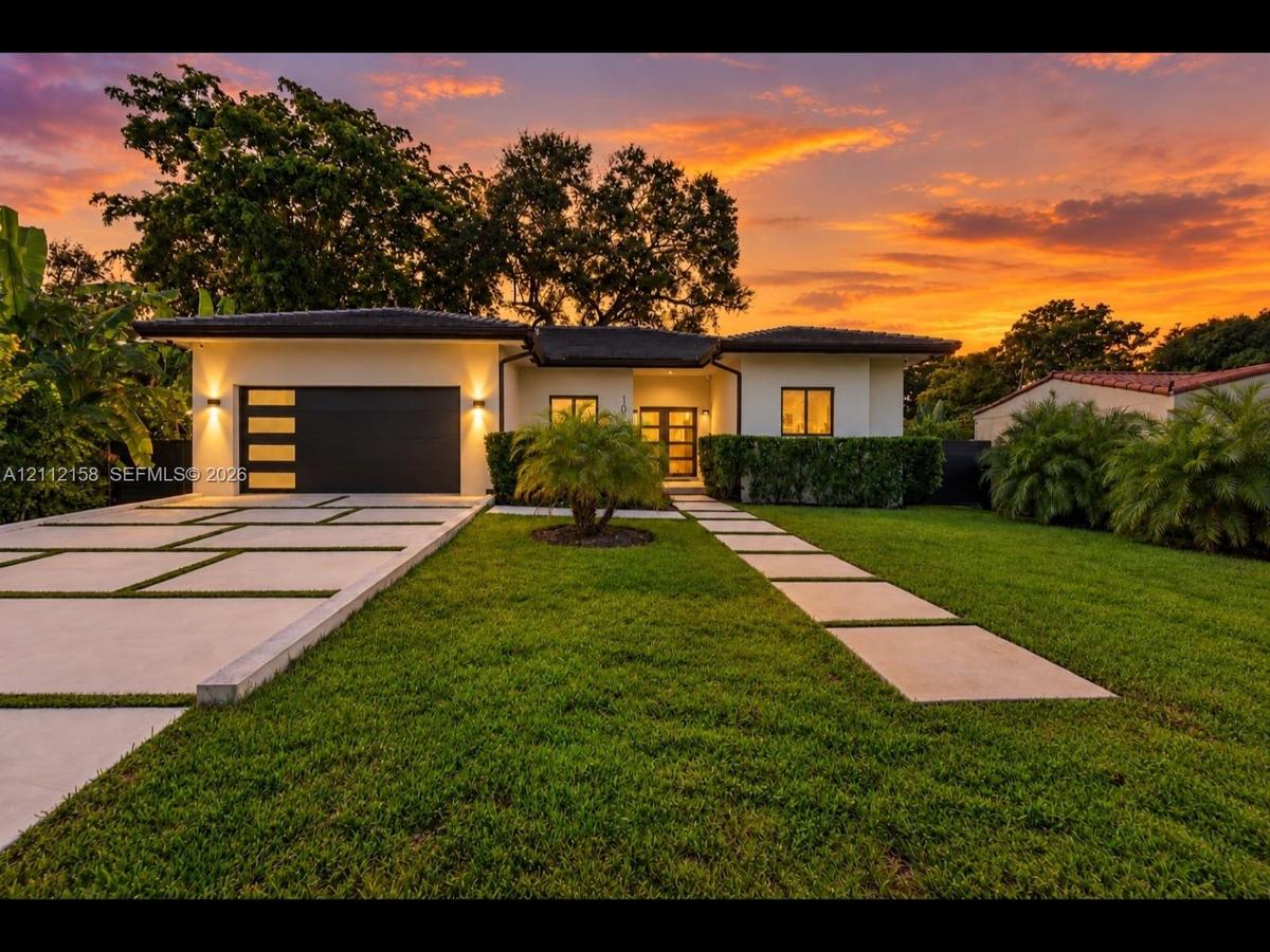 Striking contemporary exterior with a crisp facade, modern multi-panel garage door, and a stylish grass-inlay driveway leading to a recessed entry