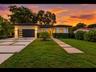 Striking contemporary exterior with a crisp facade, modern multi-panel garage door, and a stylish grass-inlay driveway leading to a recessed entry