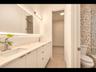Modern bathroom with a dual-sink vanity, oversized LED-lit mirror, and stylish tile shower accents
