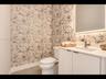 Stylish bathroom with designer patterned wallpaper, white vanity, chrome fixtures, and a modern LED-backlit mirror
