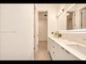Elegant dual-sink vanity with stone countertop, sleek cabinetry, LED-backlit mirror, and brushed metal hardware