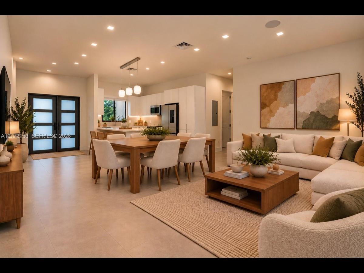 Open-concept living with large-format tile, recessed lighting, sleek white cabinetry, and an elegant double-door entry with frosted glass