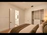Comfortable bedroom with neutral walls, and a closet with built-in shelving and drawers