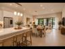 Light-filled open floor plan with quartz countertops, statement triple-pendant lighting, and sliding glass doors