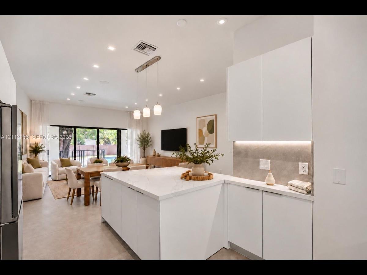 Chef-inspired kitchen with white cabinetry, under-cabinet lighting, and a designer pendant fixture
