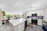 Kitchen featuring a central island with a quartz countertop, white shaker-style cabinetry with gold-tone pulls, a purple tile backsplash, large-format