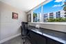 Built-in dark-toned desk with integrated cabinetry, large-format tile flooring, and oversized window featuring a polished stone sill