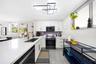 Kitchen featuring white cabinetry with brass hardware, expansive white countertops, a deep undermount sink with a brass faucet, large-format tile floo