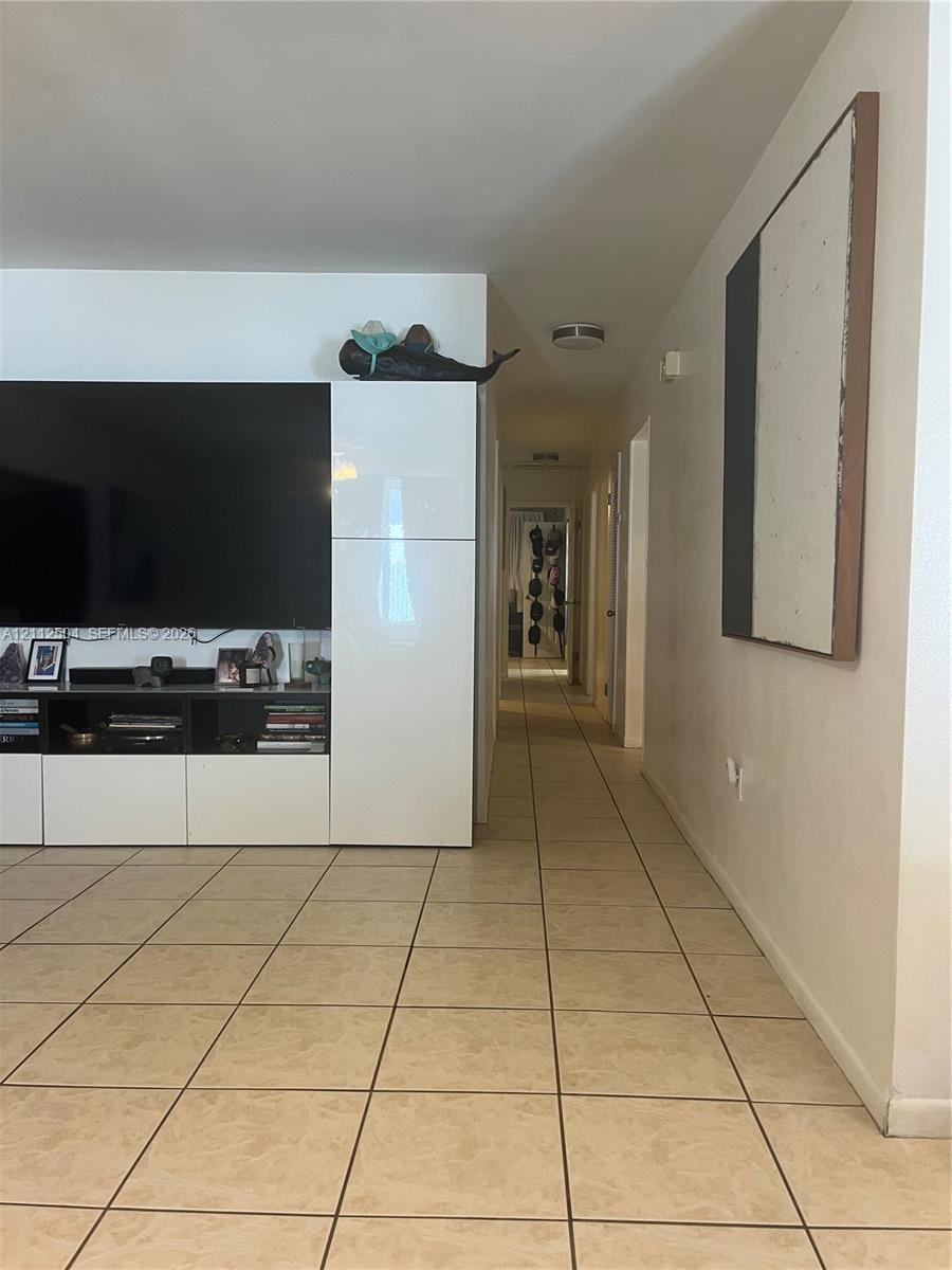Large-format square tile flooring, neutral wall finishes, and custom white built-in cabinetry featuring integrated storage