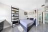 Polished tile flooring, wall-mounted black metal shelving, and sleek built-in desk cabinetry