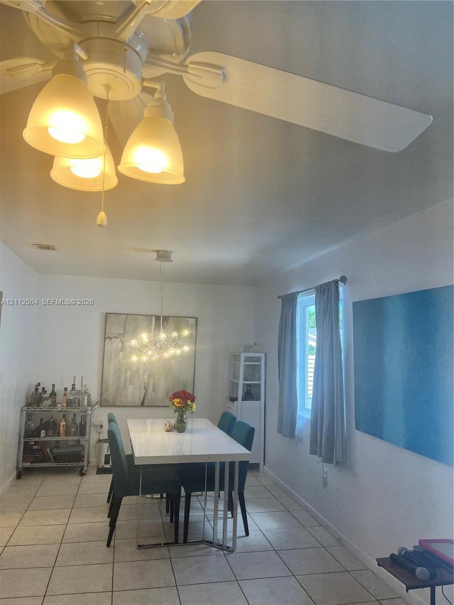 Ceramic tile flooring, white-finished ceiling, multi-light ceiling fan, and multi-light chandelier fixture